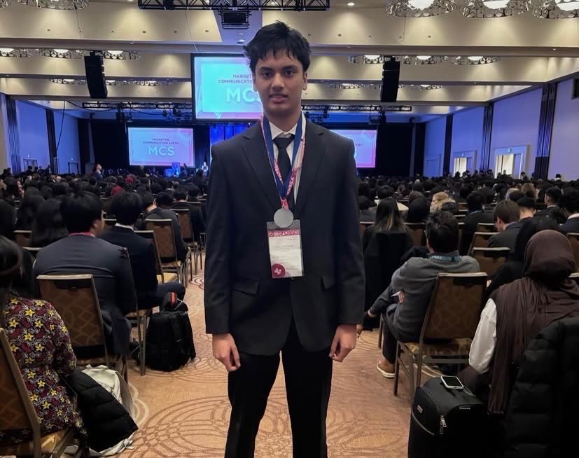 A Mother Teresa DECA student wearing a medal in the Provincials ballroom