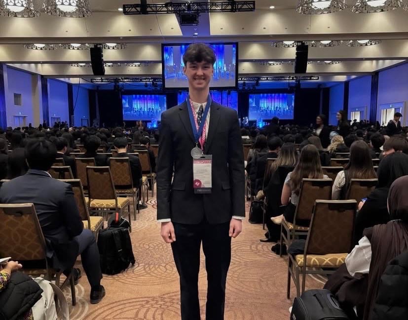 A second Mother Teresa DECA student wearing a medal in front of the main stage