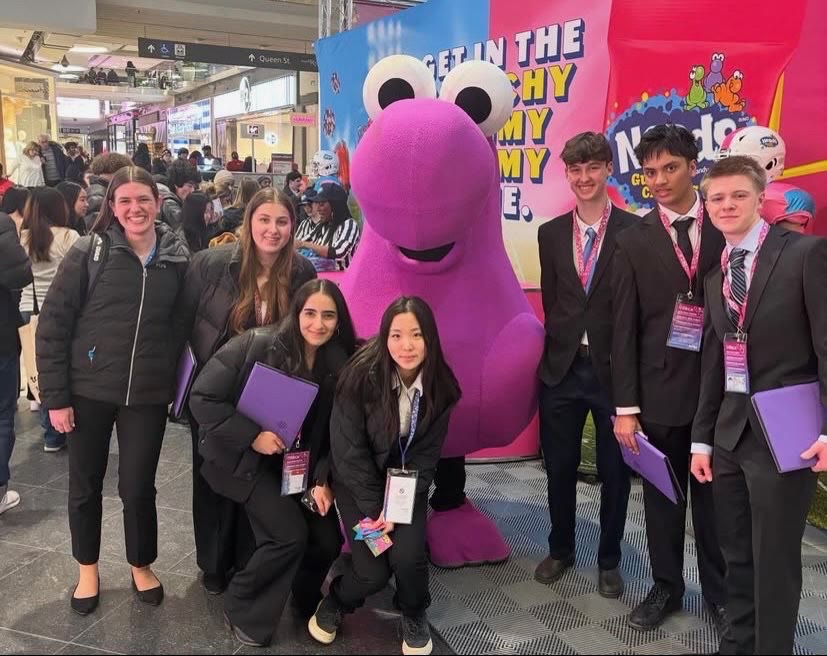 Seven Mother Teresa DECA students posing together downtown during a break between rounds